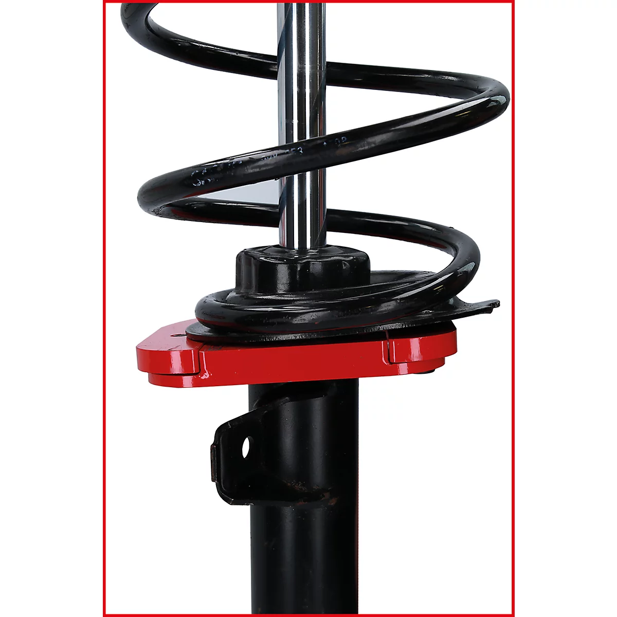 Nahaufnahme eines Stoßdämpfers. Eine schwarze Schraubenfeder windet sich um eine Metallstange. Darunter ein rotes Element und schwarze Halterung.